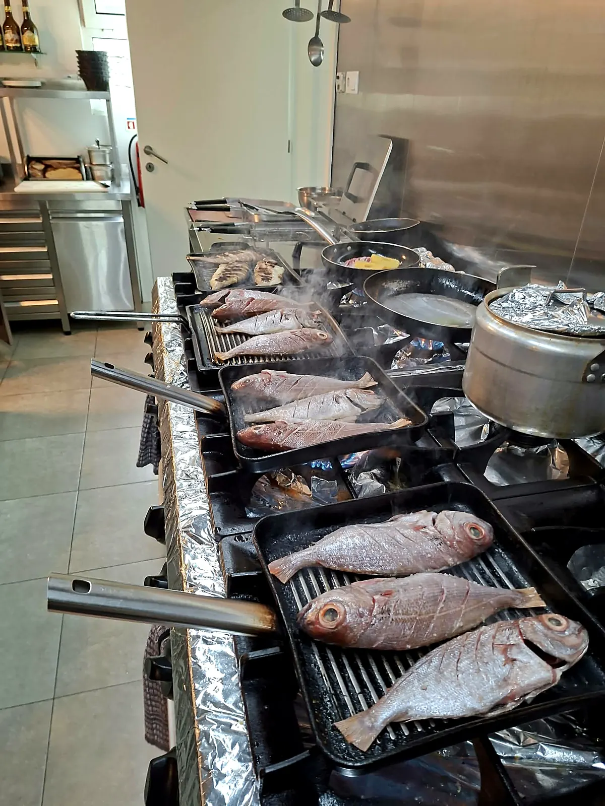 Peixes inteiros a grelhar na brasa