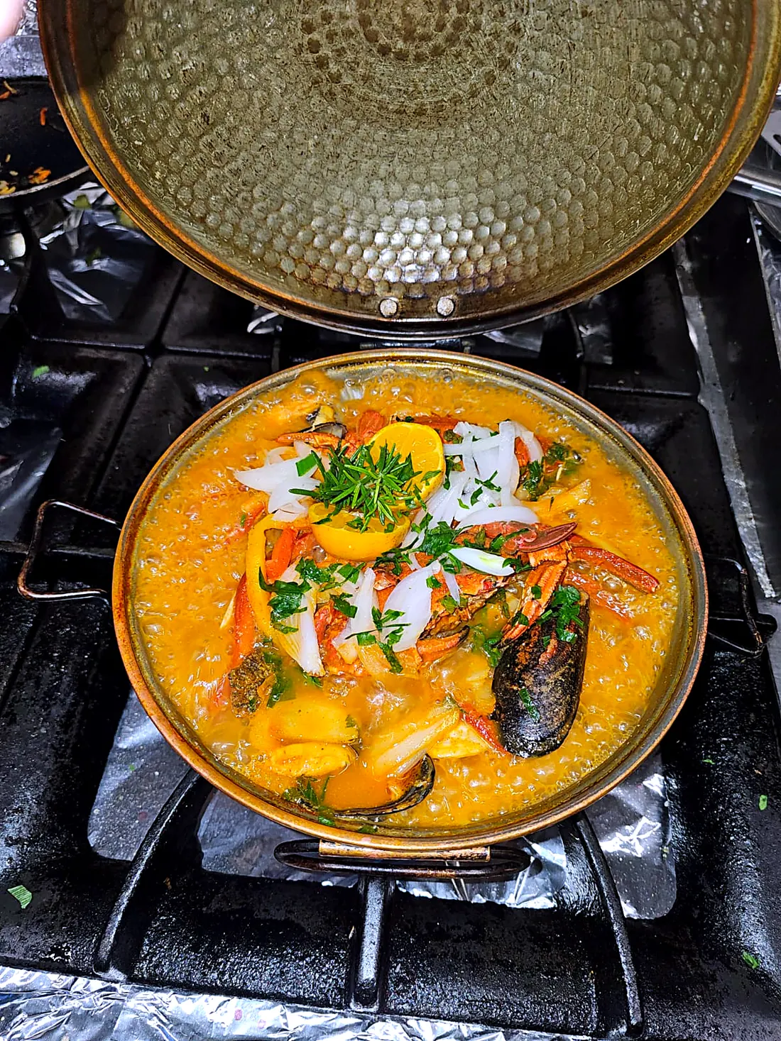 Cataplana de cobre aberta ao lume, com marisco